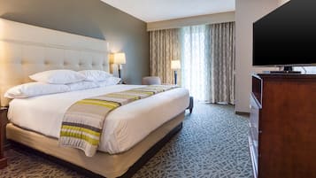 A hotel room with a large bed, two bedside lamps, a television, and a wooden dresser.