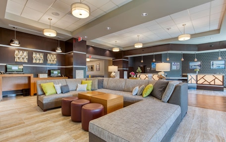 A spacious lobby with a large sectional sofa, a reception desk, and a modern chandelier.