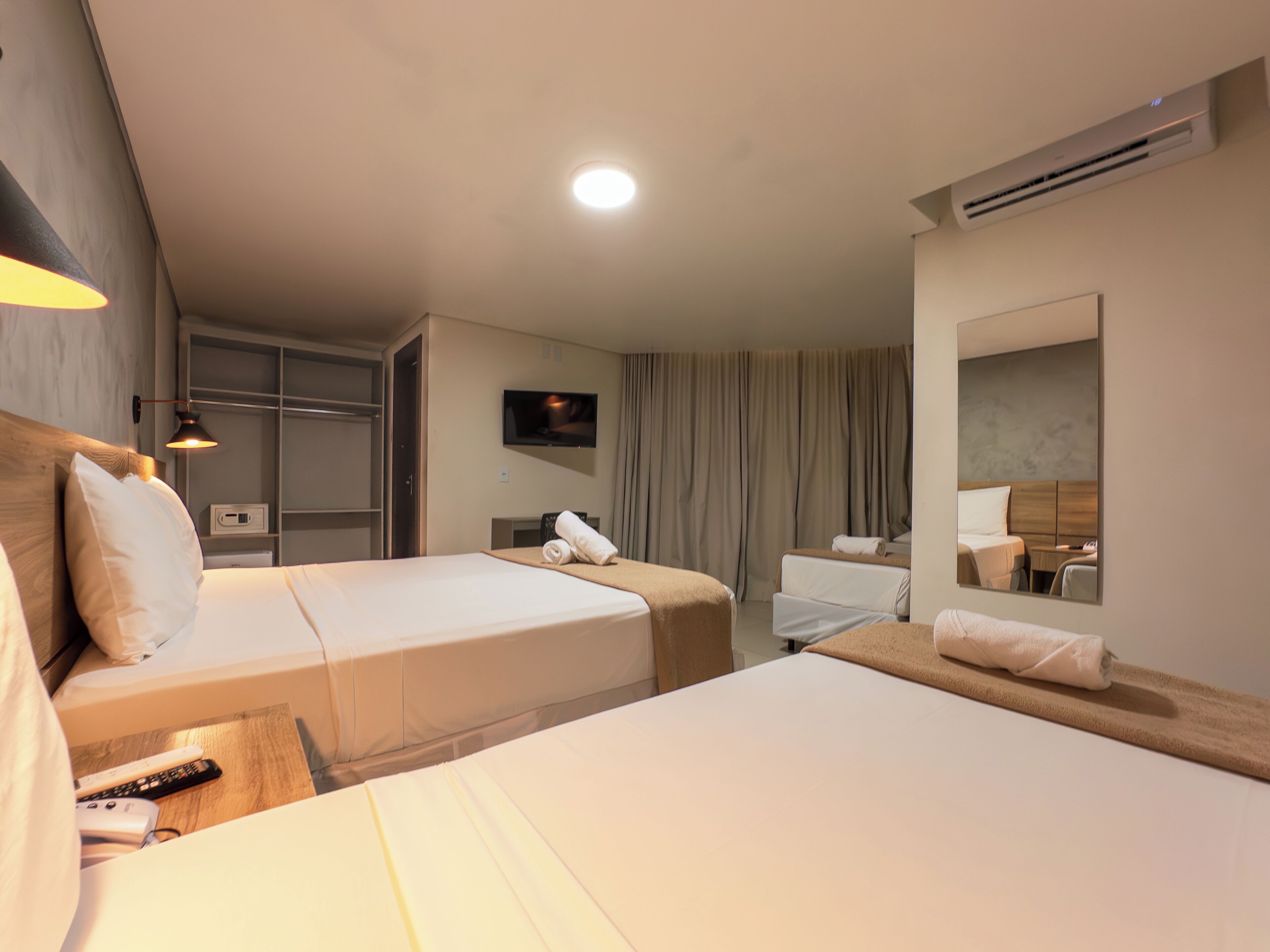 Une chambre d’hôtel avec deux lits, une télévision, un miroir et une armoire.
