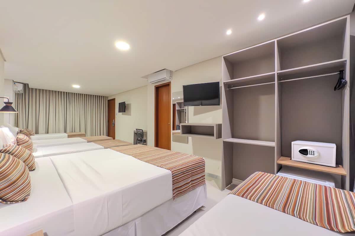 A hotel room with two beds, a TV, a wardrobe, and a desk.