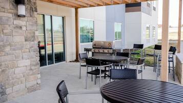 An outdoor patio with stone walls, a grill, and multiple tables and chairs.