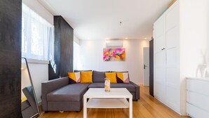 A modern living room with a sectional sofa, a white coffee table, and a colorful abstract painting.