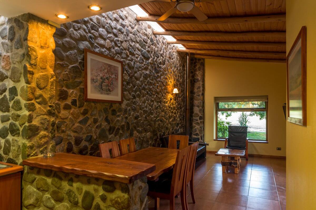 A dining area with a stone wall, wooden table, and chairs.