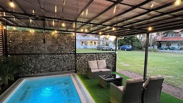 Relax by the rectangular pool surrounded by lush greenery and comfortable lounge chairs.