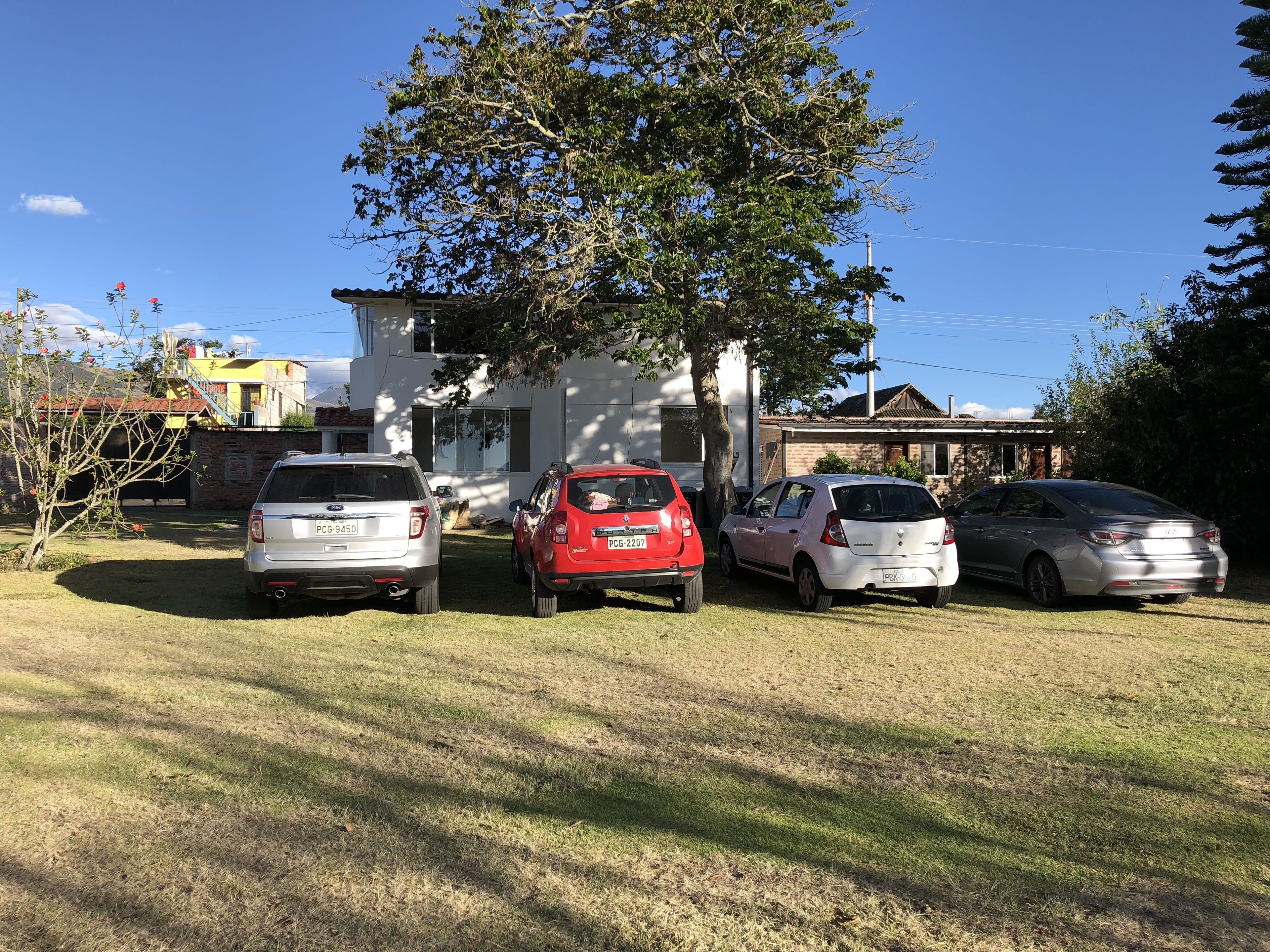 Zona residenziale con tre auto parcheggiate davanti a una casa.