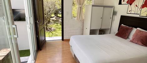 A bedroom with a large bed, a wardrobe, and a sliding glass door leading to a balcony.