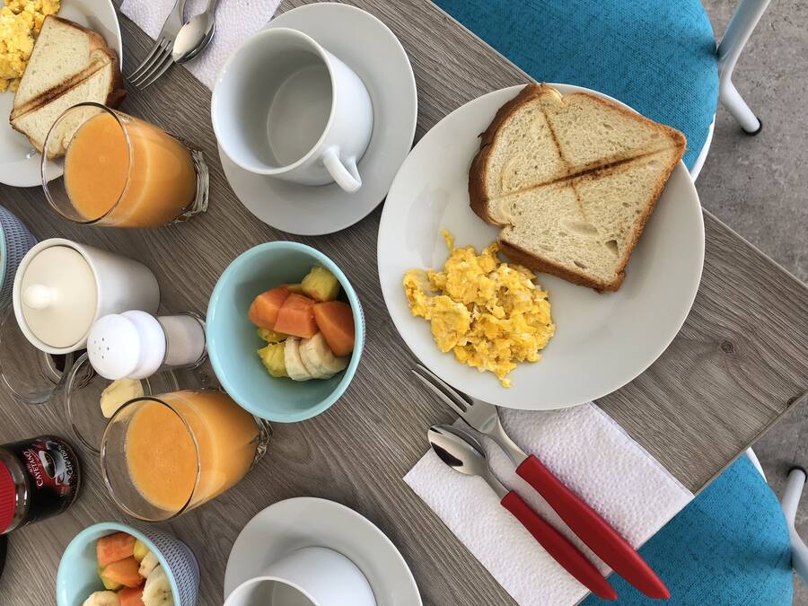A breakfast table with scrambled eggs, toast, fruit, and juice.