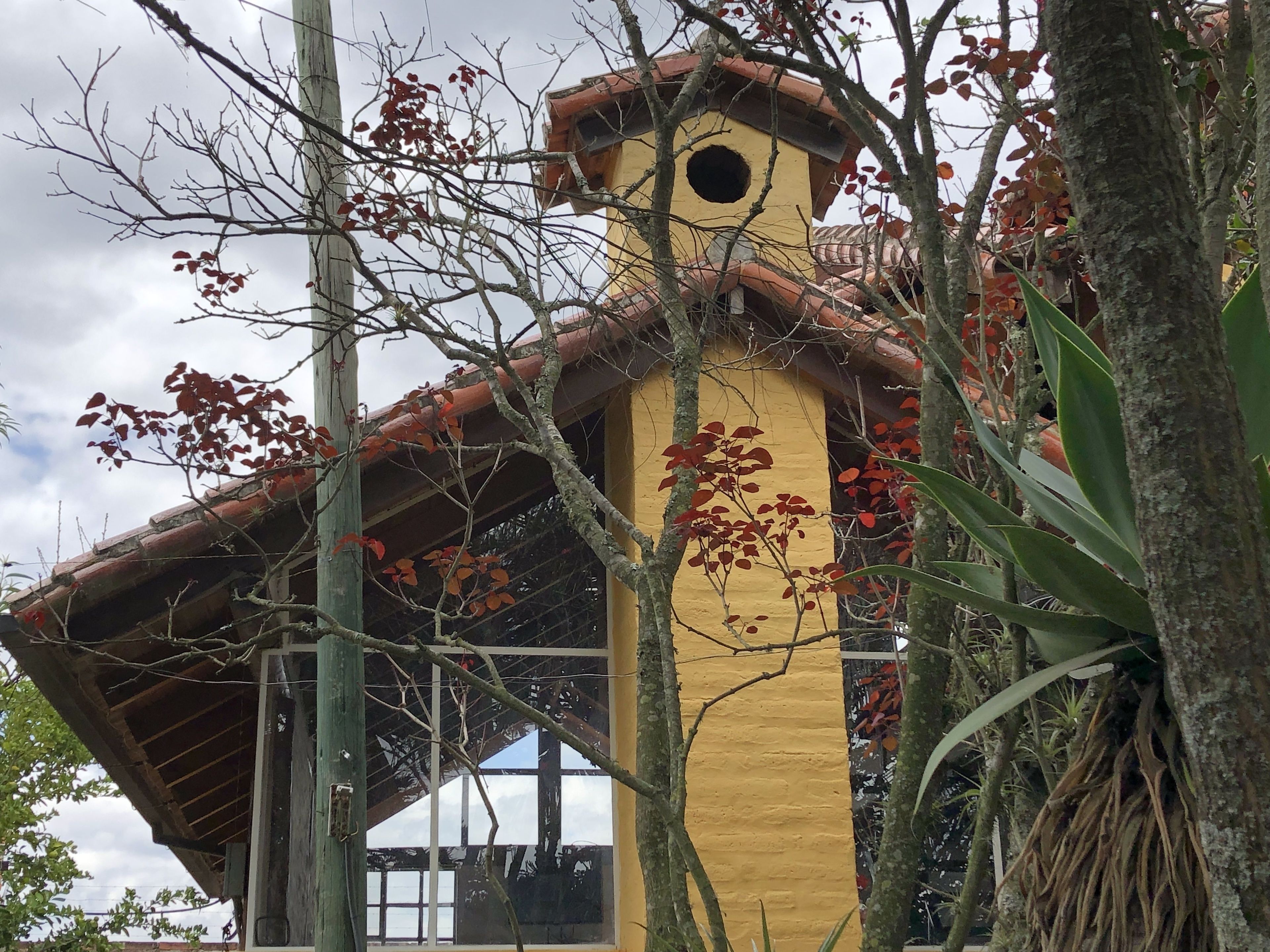A yellow building with a red-tiled roof and a circular window.