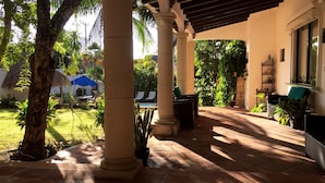 Un patio cubierto con suelo de piedra, columnas y plantas en macetas.