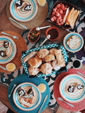 A table set with various dishes including bread, fruit, and condiments, suggesting a meal setup.