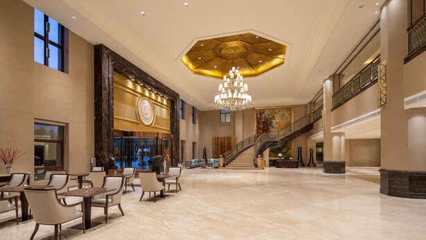 A spacious lobby with a grand chandelier, a staircase, and a seating area with tables and chairs. - Holiday Inn Fuzhou New Port by IHG (Fuzhou)