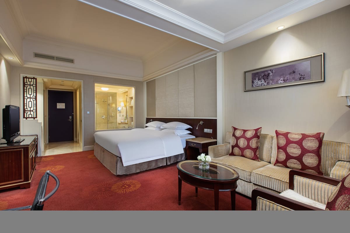 A hotel room with a bed, a sofa, a TV, and a desk.