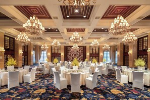 A banquet hall with multiple round tables, white chairs, chandeliers, and a patterned carpet. - Holiday Inn Fuzhou New Port by IHG (Fuzhou)