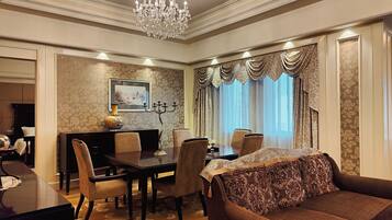 A dining area with a chandelier, a dining table, chairs, and a sofa.