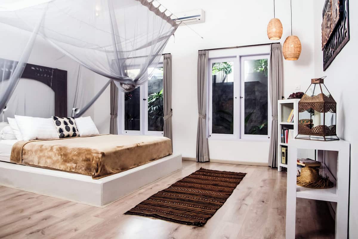 A bedroom with a bed, a window, a bookshelf, and a decorative lantern.