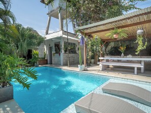 A swimming pool with lounge chairs, a covered seating area, and various potted plants. - Lila Boutik Canggu (Canggu)
