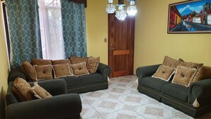 A living room with two sofas, patterned cushions, a wooden door, and a tiled floor. - Casa hermosa a 20 minutos del aeropuerto (Guatemala City)