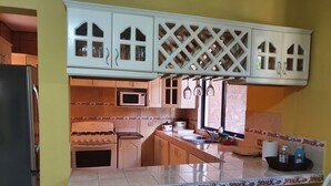 A kitchen with white cabinets, a stove, a microwave, and a sink. - Casa hermosa a 20 minutos del aeropuerto (Guatemala City)