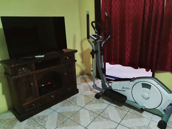 Una habitación con un armario de madera, un televisor y una bicicleta estática.