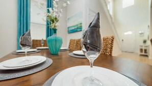 A dining table set with white plates, clear glasses, and a folded napkin.