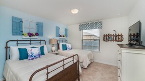 A bedroom with two beds, a dresser, a window with blinds, and decorative wall art.