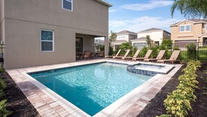 A rectangular swimming pool with a tiled edge, surrounded by lounge chairs and a patio area. - The Encore Club #7 - 8 Bed 7 Baths Villa (Kissimmee)
