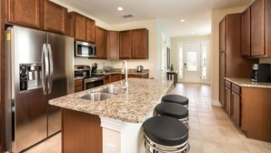 A modern kitchen with stainless steel appliances, granite countertops, and wooden cabinets. - The Encore Club #7 - 8 Bed 7 Baths Villa (Kissimmee)