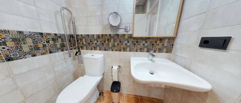Une salle de bain comprenant des toilettes, un bidet, un lavabo et un miroir.