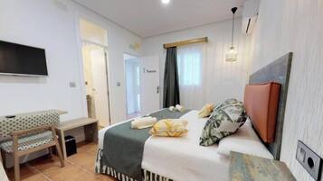 Una habitación de hotel con cama, escritorio, silla, televisor y puerta.