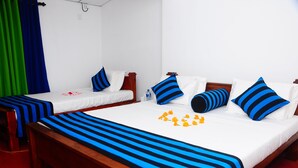 A hotel room with two single beds, each with blue and white bedding, and a large bed with blue and white bedding. - Sun Ceylon Habarana (Sigiriya)