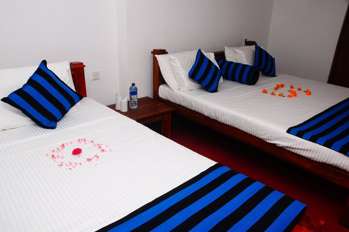 Two beds with white and blue striped bedding, a water bottle on the nightstand, and orange flowers on the bed.