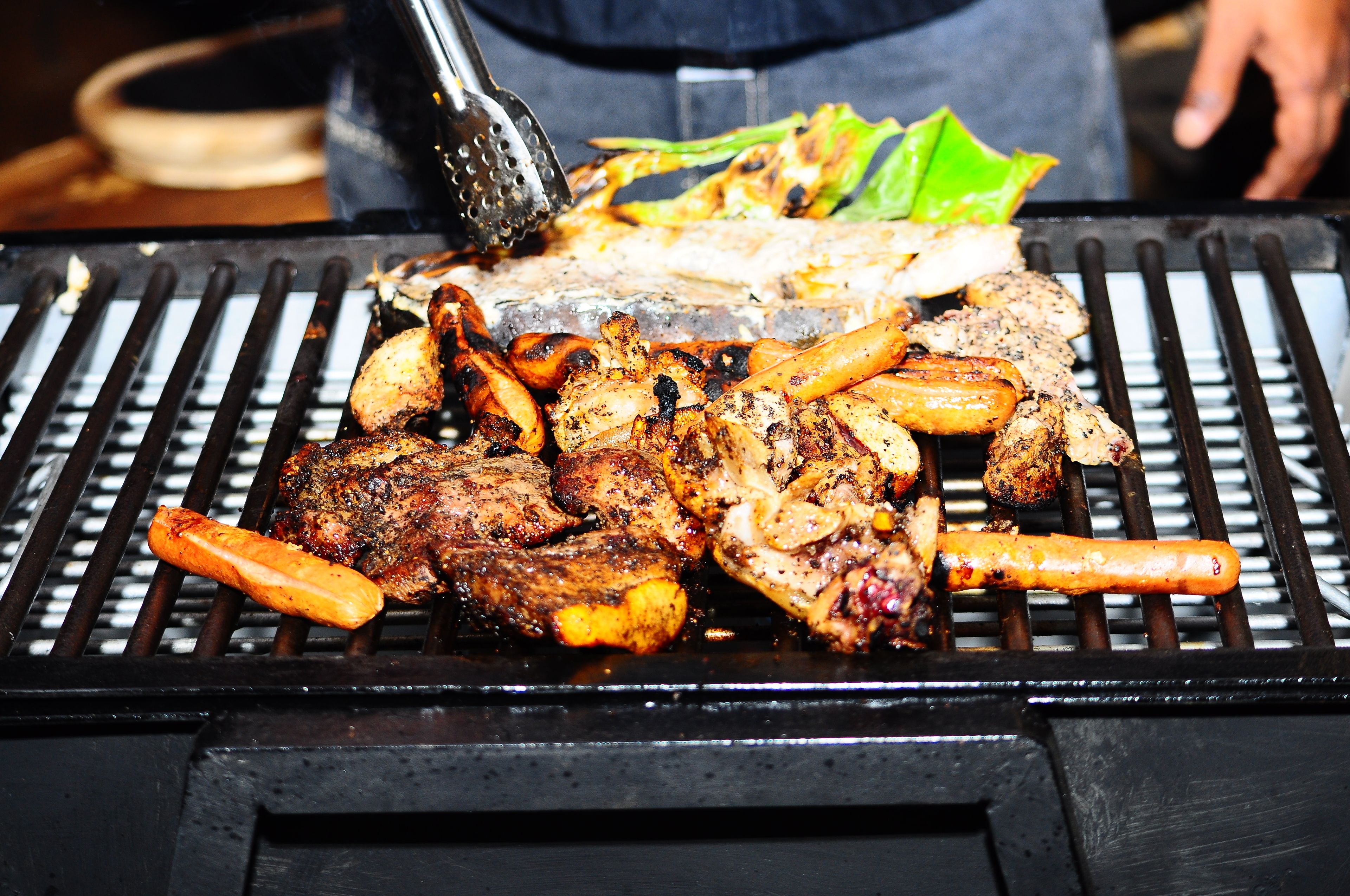 Ein Grill mit verschiedenen Fleischsorten und Gemüse, das zubereitet wird.