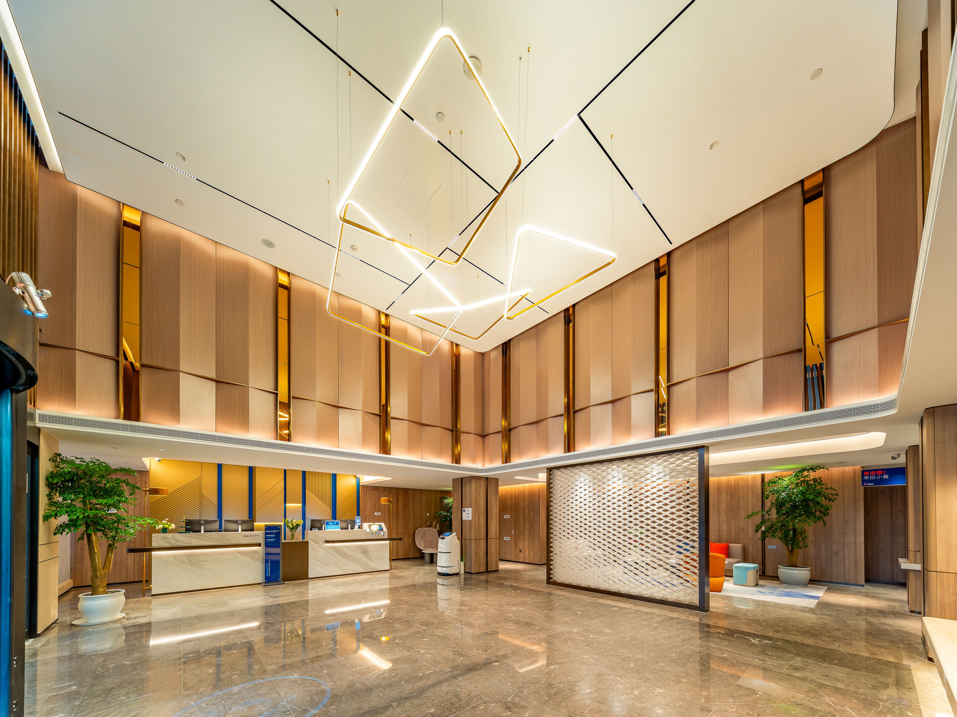 A spacious lobby with a reception desk, modern lighting fixtures, and a large plant.