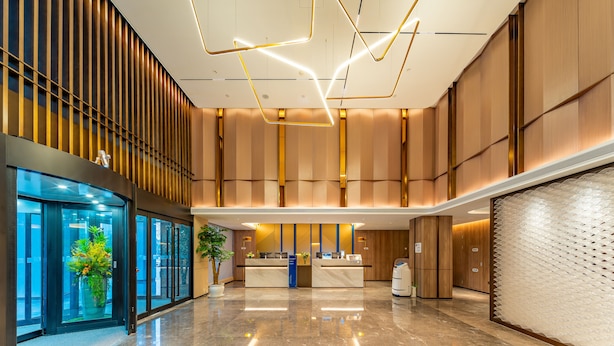 A modern hotel lobby with a reception desk, a plant, and a glass elevator. - Holiday Inn Express Hefei Ftz by IHG (Hefei)