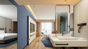 A modern hotel room with a large bed, a white bathroom with a large mirror, and a small seating area with a table and chairs. - Holiday Inn Express Hefei Ftz by IHG (Hefei)
