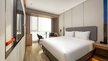 Een moderne hotelkamer met een groot bed, een bureau en een stoel.