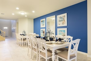 A dining area with white tables and chairs, blue walls, and framed pictures.