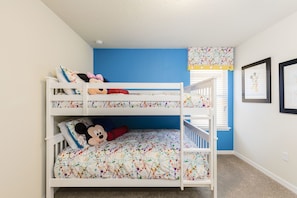 Quarto com beliche, parede azul como detalhe, um brinquedo de pelúcia do Mickey Mouse e quadros nas paredes.