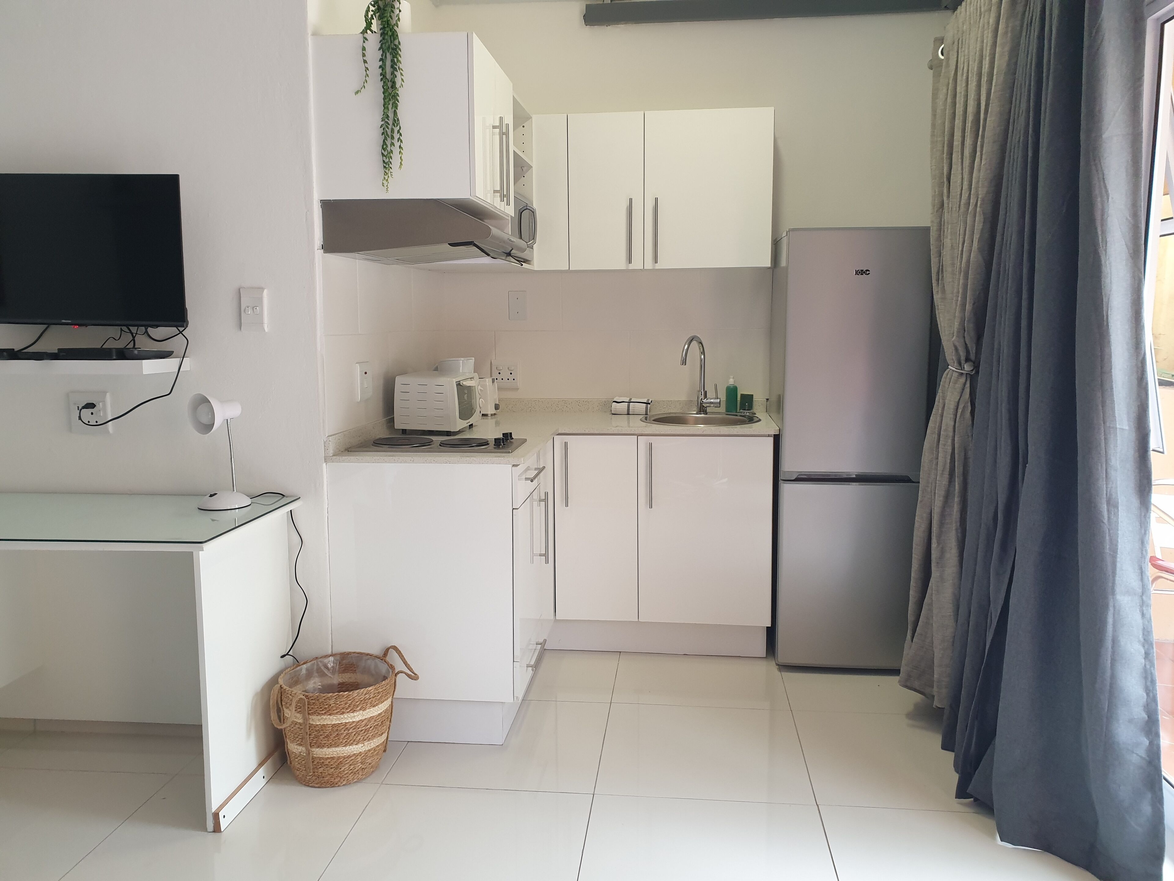 A compact kitchen with white cabinets, a microwave, a sink, and a refrigerator.