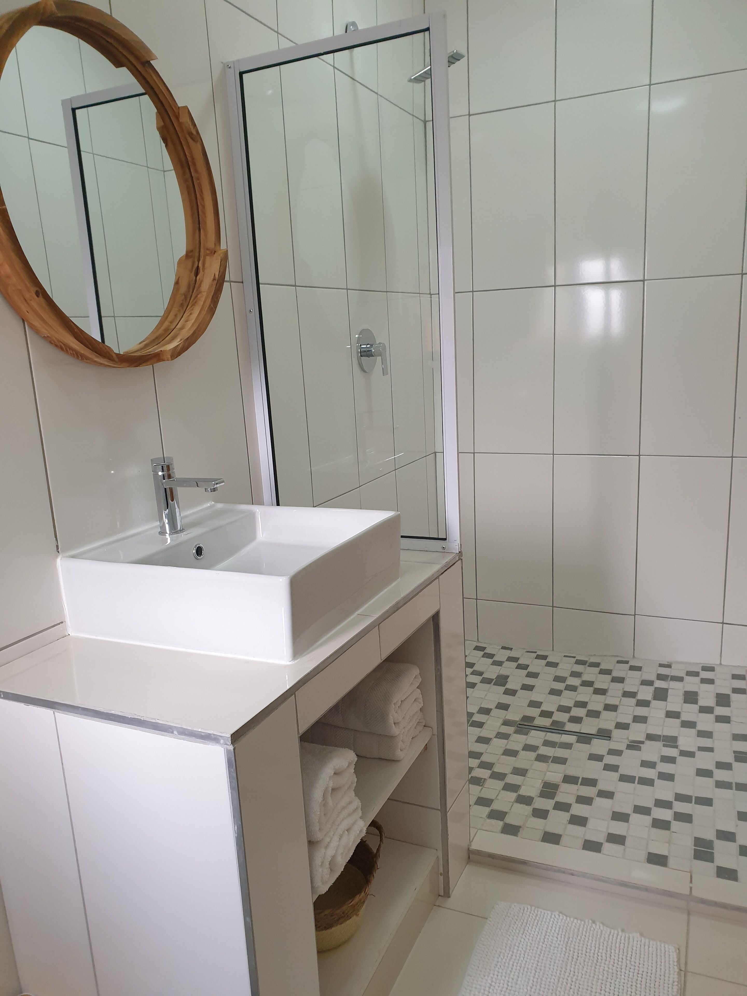 A bathroom with a white sink, a mirror, and a shower enclosure.
