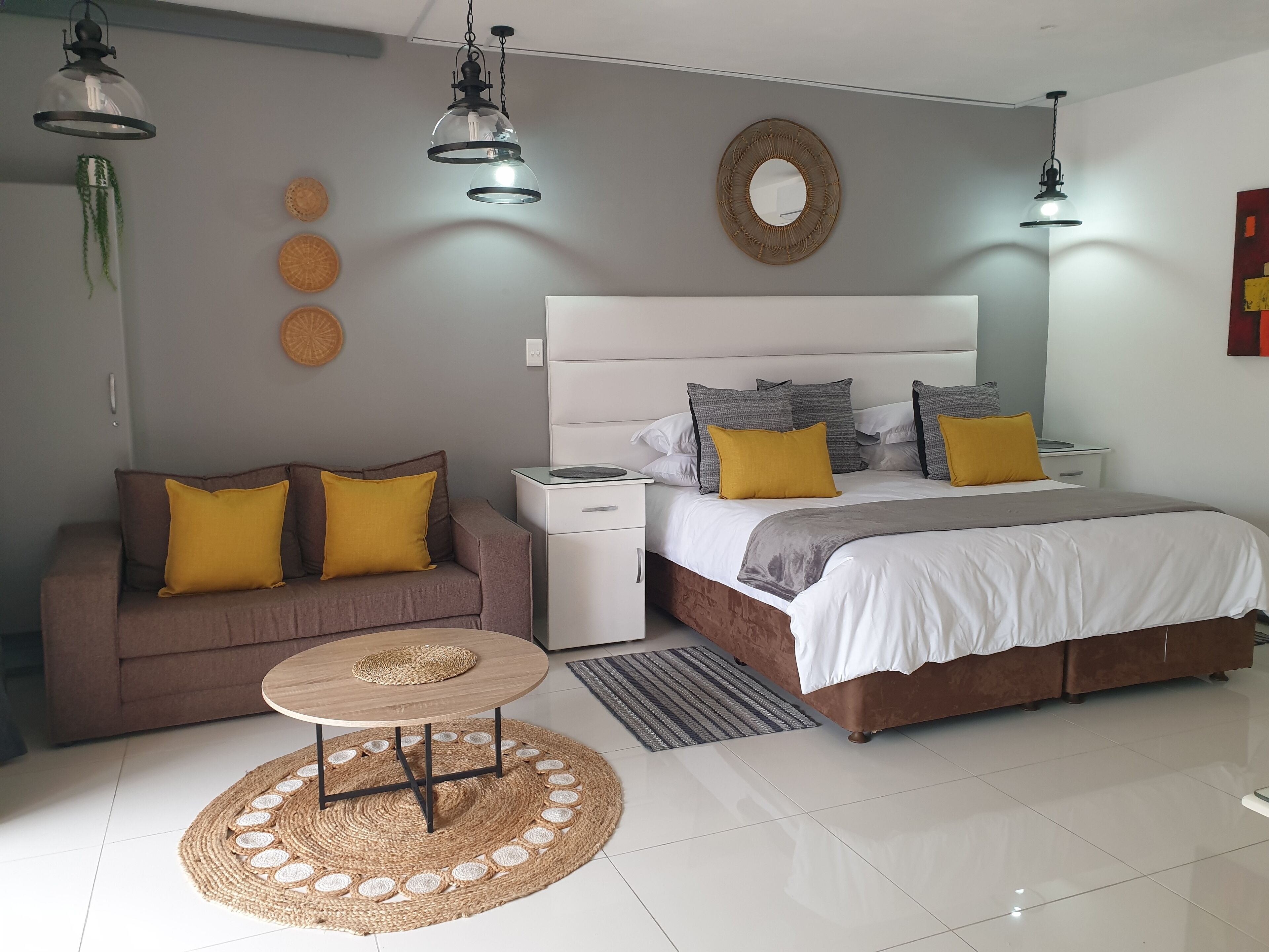 A modern bedroom with a bed, bedside tables, a sofa, and a round table.