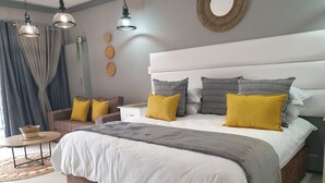 Un dormitorio moderno con una cama grande, mesitas de noche, una pequeña mesa redonda y un adorno en la pared.