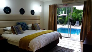 Un dormitorio con una cama grande, vista a una piscina y una señal de salida.