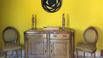 Un mueble de madera con dos cajones y un estante, flanqueado por dos sillas de mimbre con asiento y respaldo tejido.