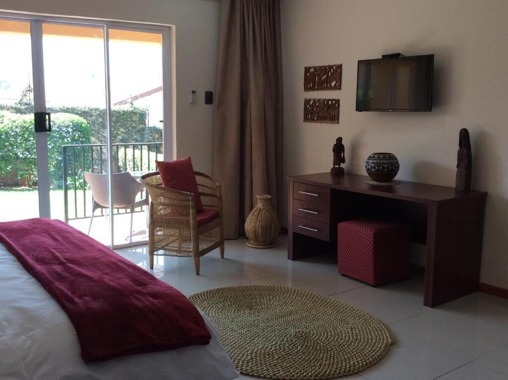 Une chambre à coucher comprenant un lit, un bureau, une chaise, un téléviseur et une vue sur l’extérieur.