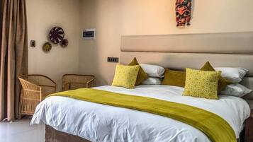A bedroom with a large bed, two bedside tables, a wall-mounted air conditioner, and a decorative wall piece.