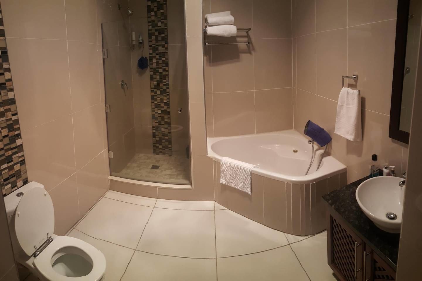 Un baño moderno con ducha a ras de suelo, bañera, inodoro y lavabo.