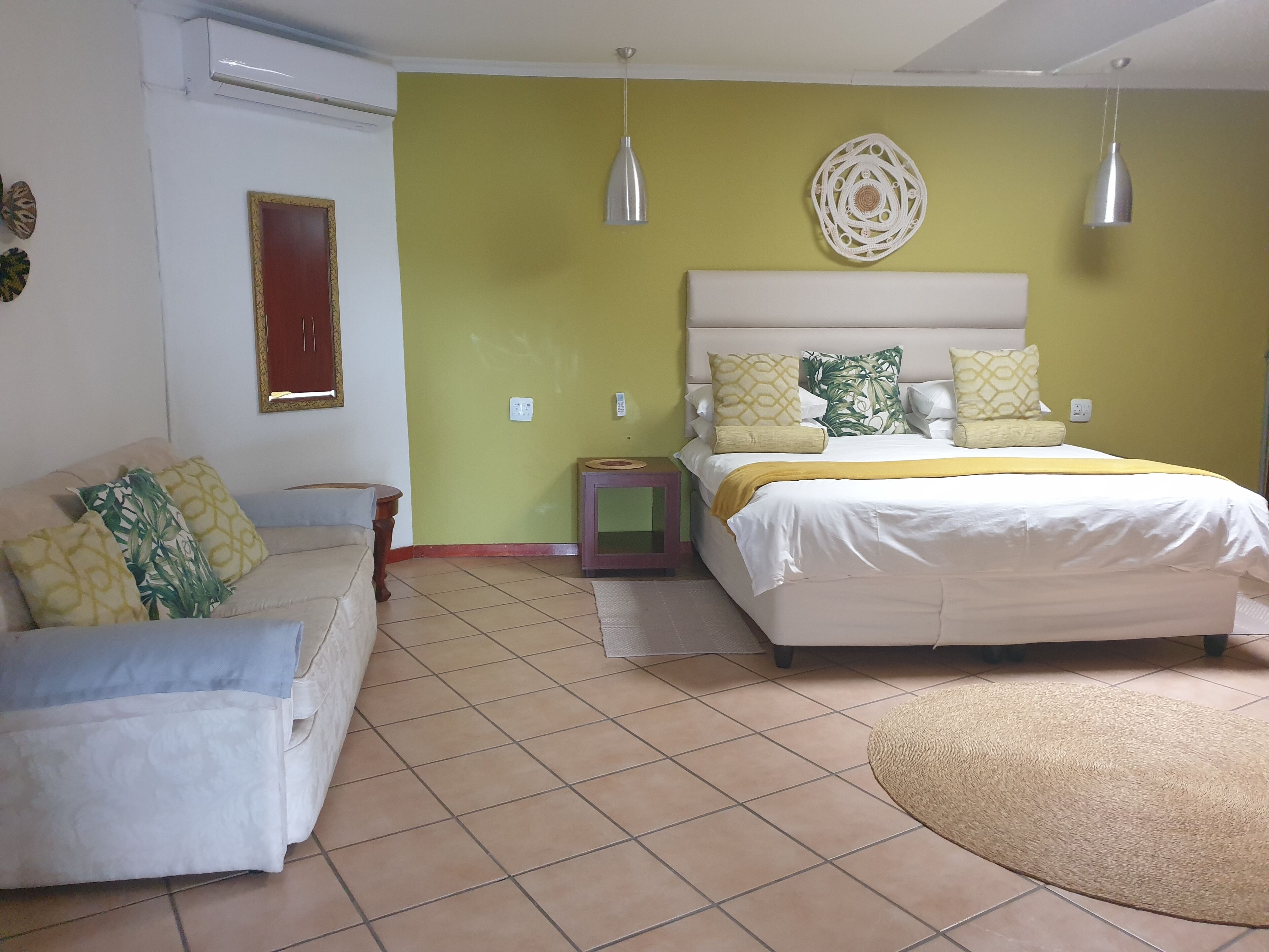 A bedroom with a bed, bedside table, and a couch.