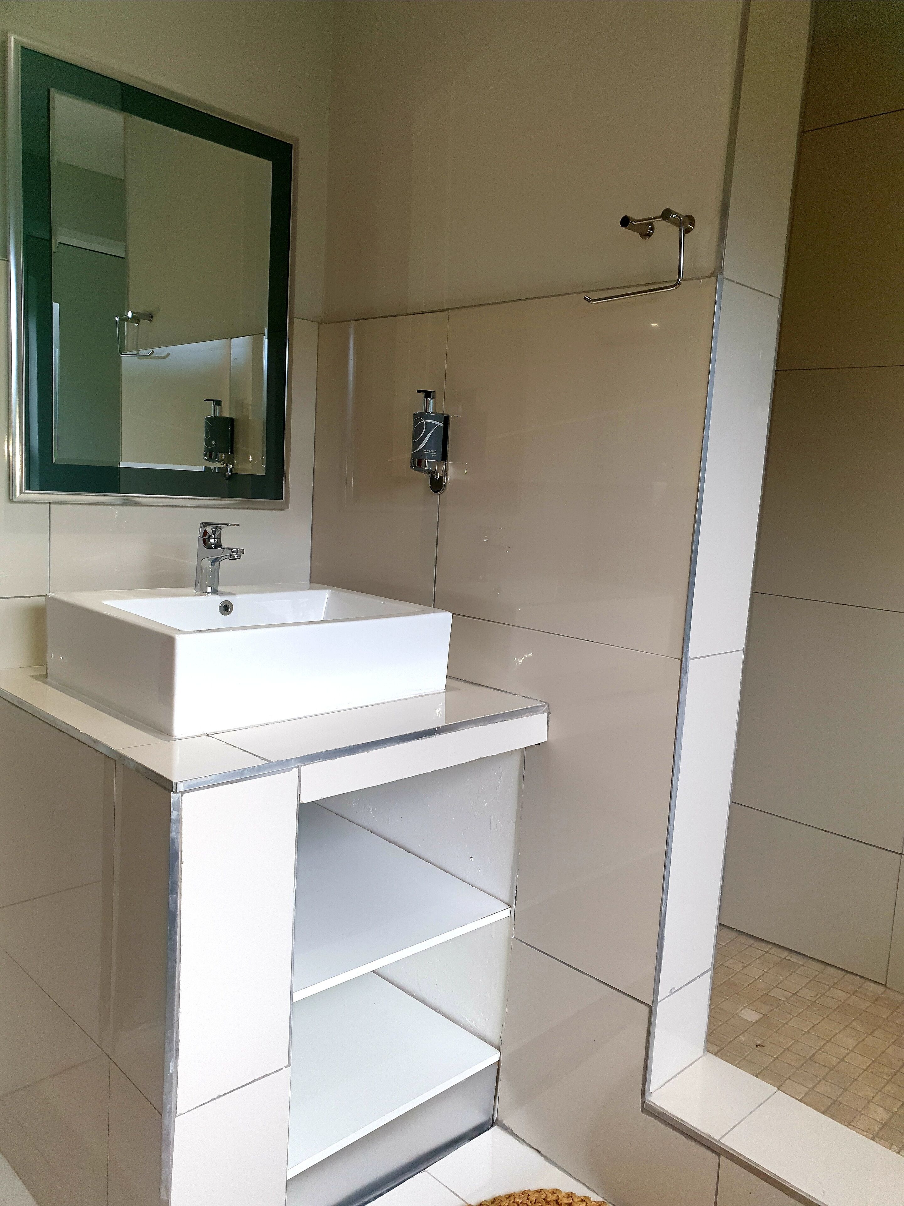 A modern bathroom with a white sink, mirror, and shower.