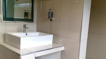 A modern bathroom with a white sink, mirror, and shower.